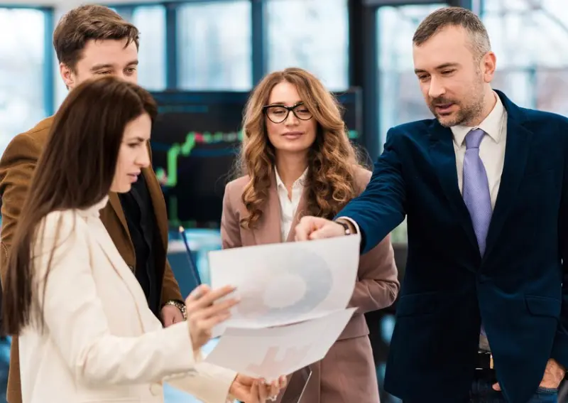 Business Team Reviewing Reports Together Business professionals examining charts and reports in office business directory